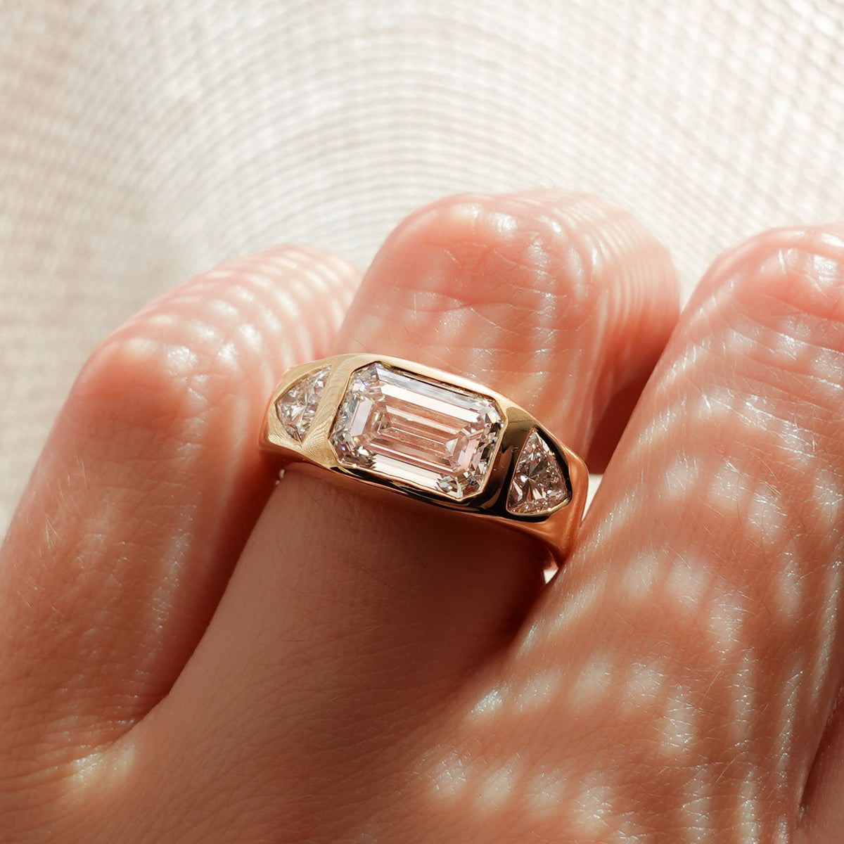 Burnished Three Stone Engagement Ring with Trilliant Sides and East West Emerald Cut Diamond