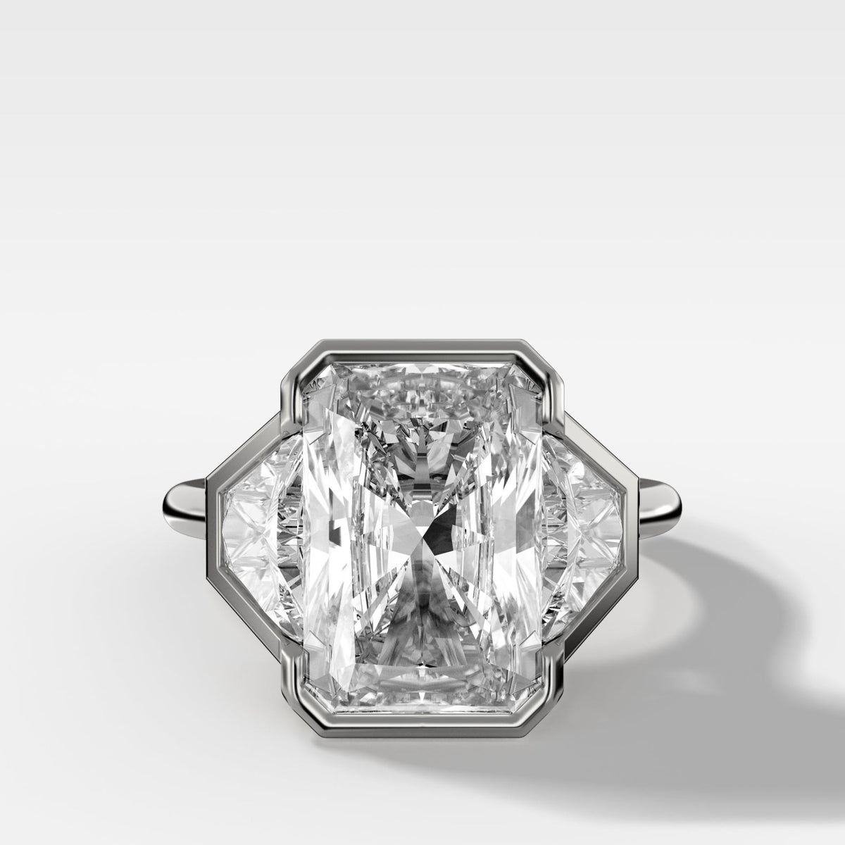 Three Stone Bezel Set Engagement Ring with Trapezoid Side Diamonds and an Elongated Radiant Cut - GOODSTONE