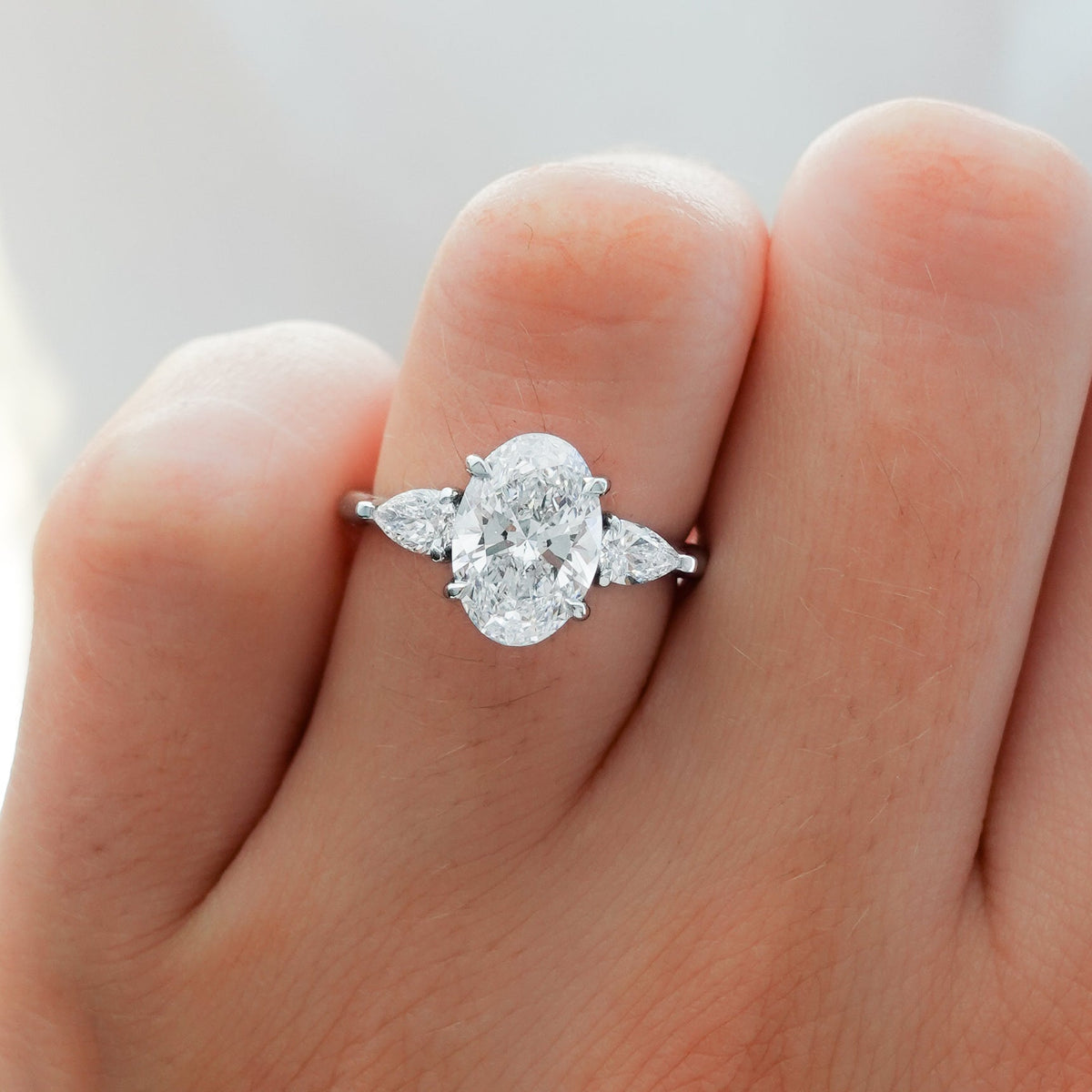 Three Stone Engagement Ring With Pear Side Stones and Oval Cut Diamond - GOODSTONE