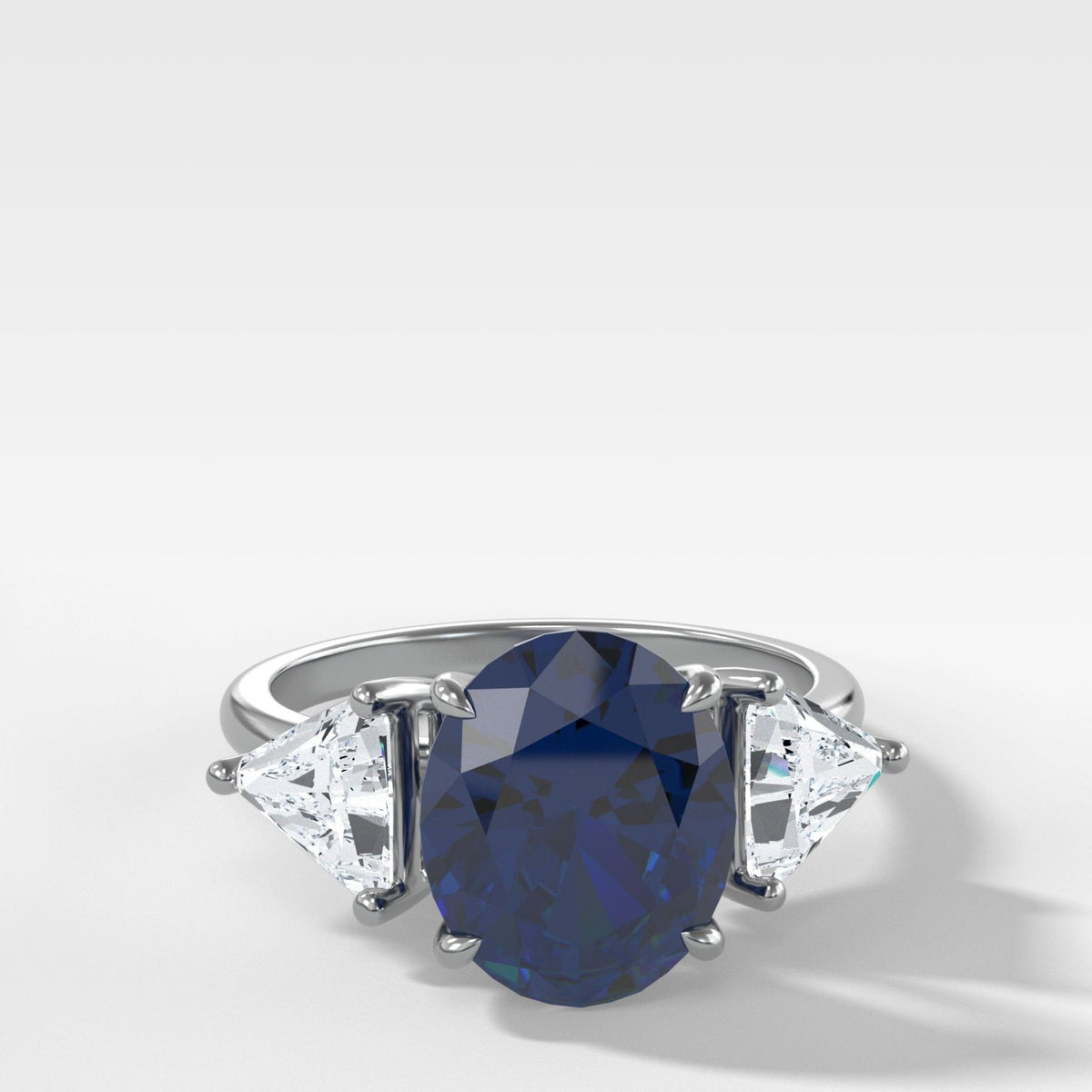 Anillo de compromiso de tres piedras con zafiro de talla ovalada y lados de diamantes de talla trilliant de Good Stone en oro blanco