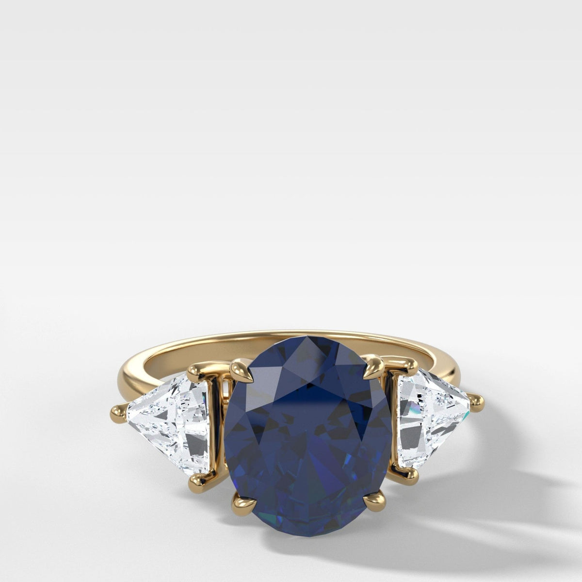 Anillo de compromiso de tres piedras con zafiro de talla ovalada y lados de diamantes de talla trilliant de Good Stone en oro amarillo