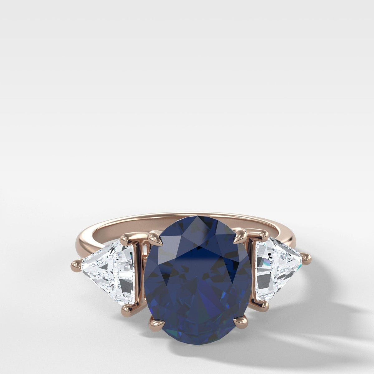 Anillo de compromiso de tres piedras con zafiro de talla ovalada y lados de diamantes de talla trilliant de Good Stone en oro rosa